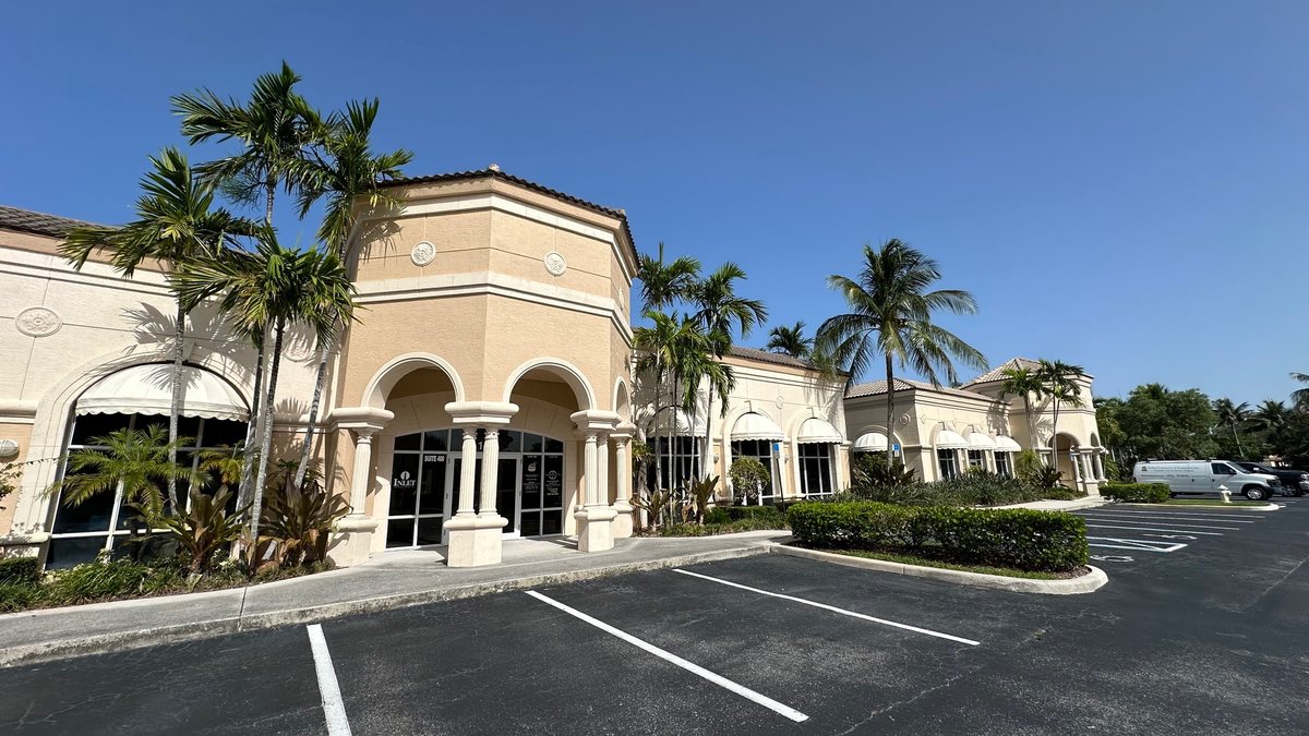 Exterior of the Intracoastal Pointe plaza in Jupiter where Sunset Smiles is located, framed by palm trees