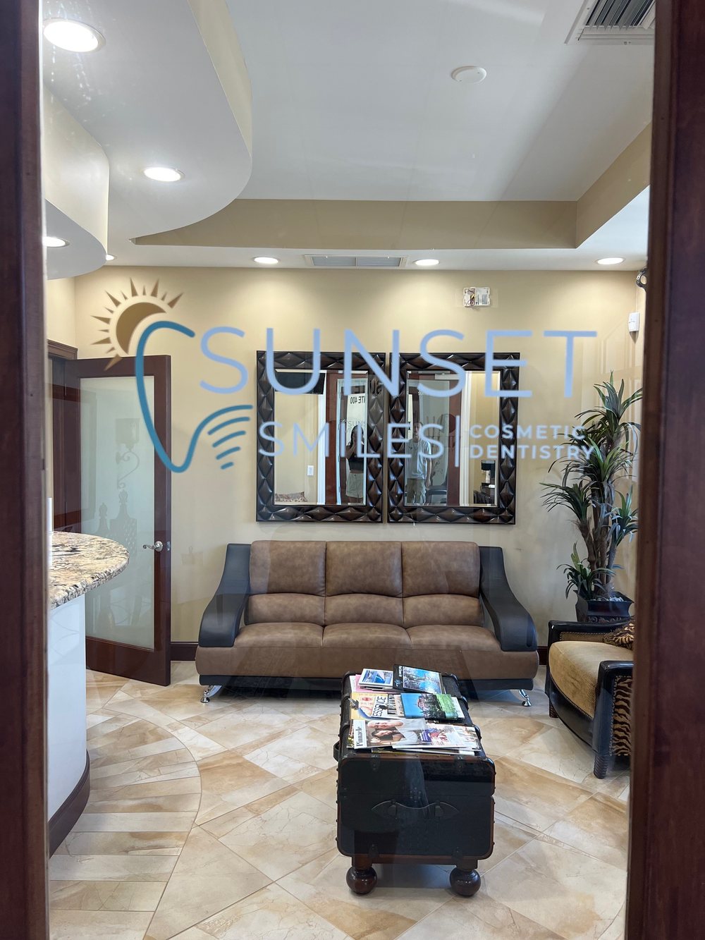 Sunset Smiles waiting room with the practice logo etched on the glass, leather seating and tile floor