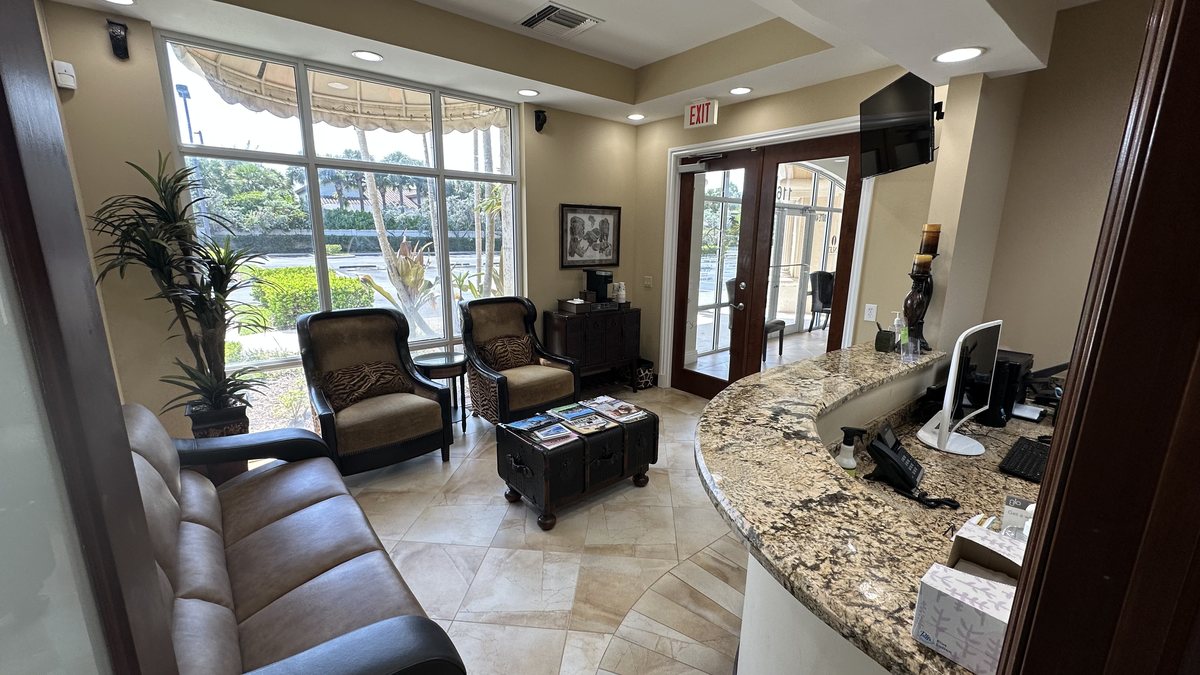 Reception desk and comfortable seating area at Sunset Smiles, with large windows and natural light