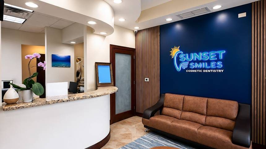 Reception area with the Sunset Smiles logo wall and a leather sofa
