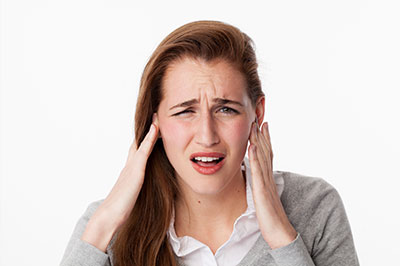 The image features a young woman with her hand on her head, appearing to be in pain or discomfort, possibly due to a headache or similar issue.
